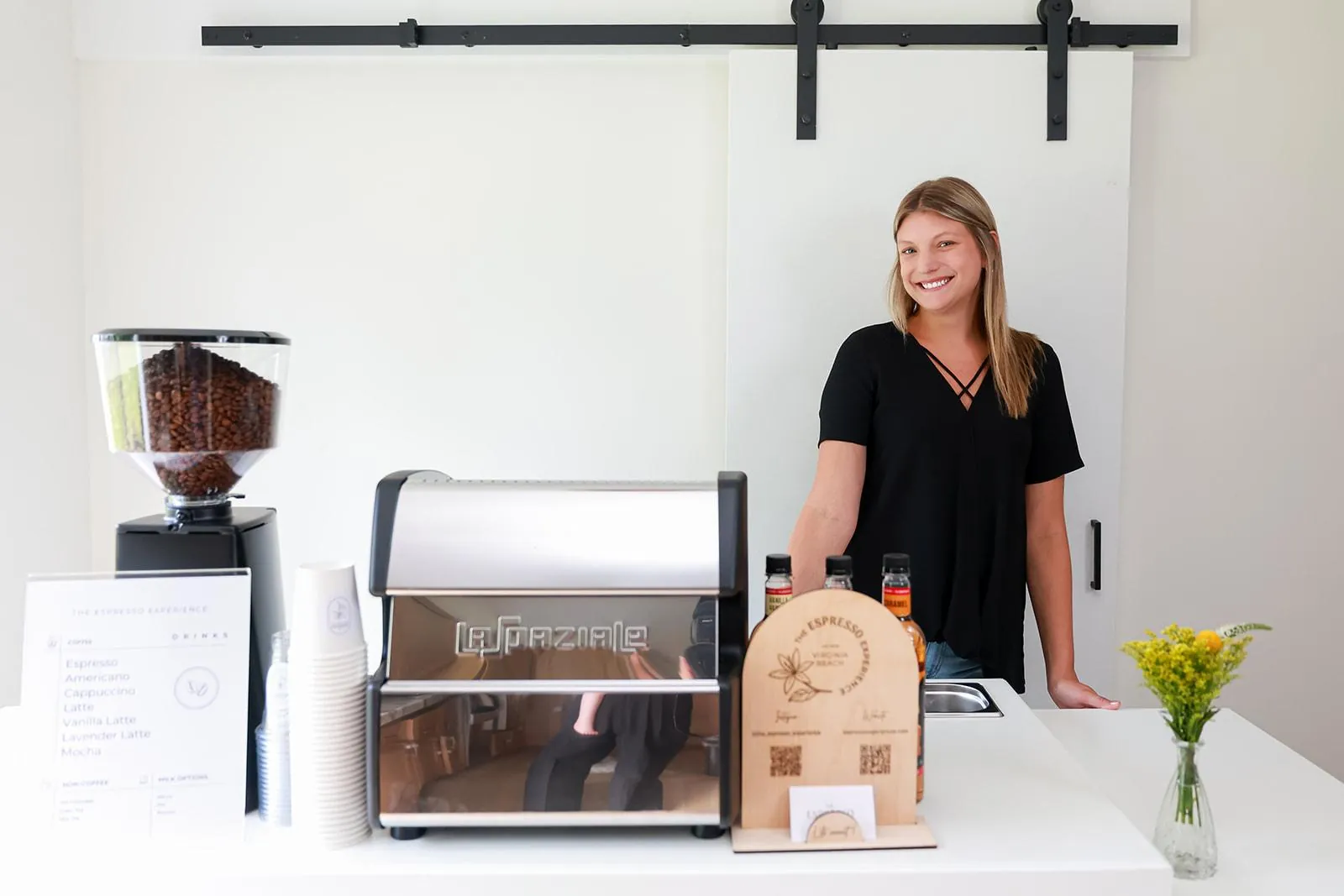 Barista behind an Italian La Spaziale espresso machine on the white coffee cart