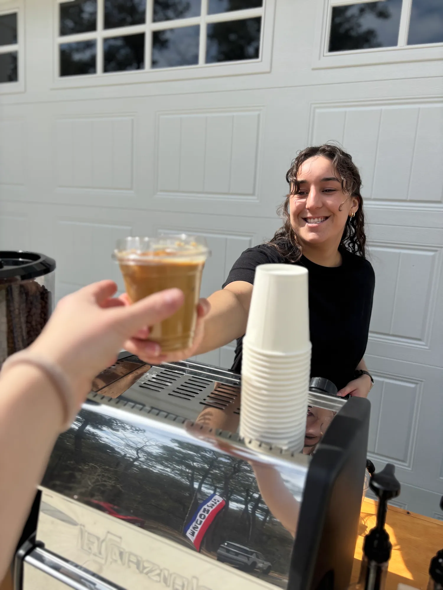 Barista handing an iced latte to a guest over the espresso machine