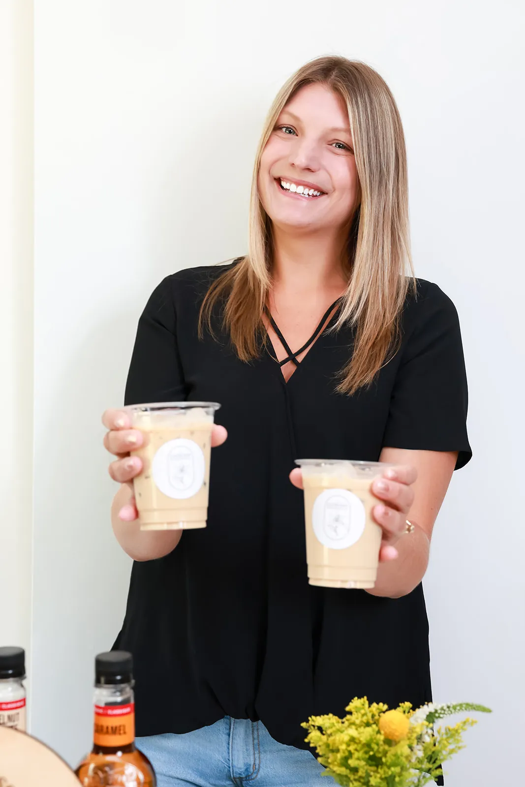 Barista smiling and holding up two iced lattes