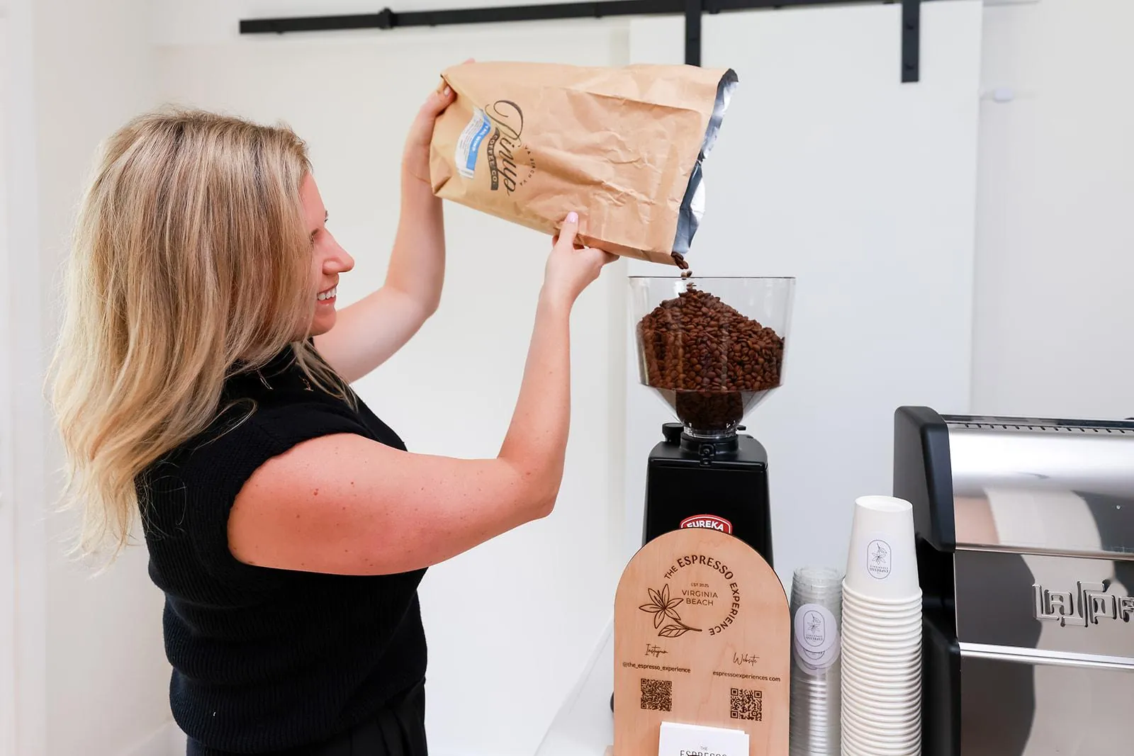 Barista pouring locally roasted coffee beans into the espresso grinder