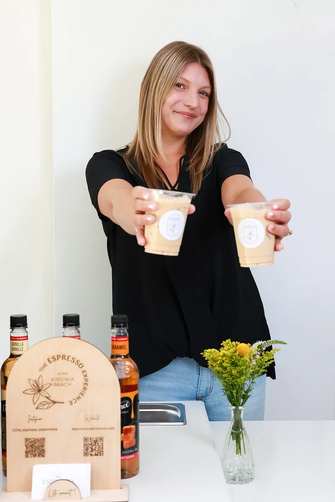 Barista offering two iced lattes across the cart