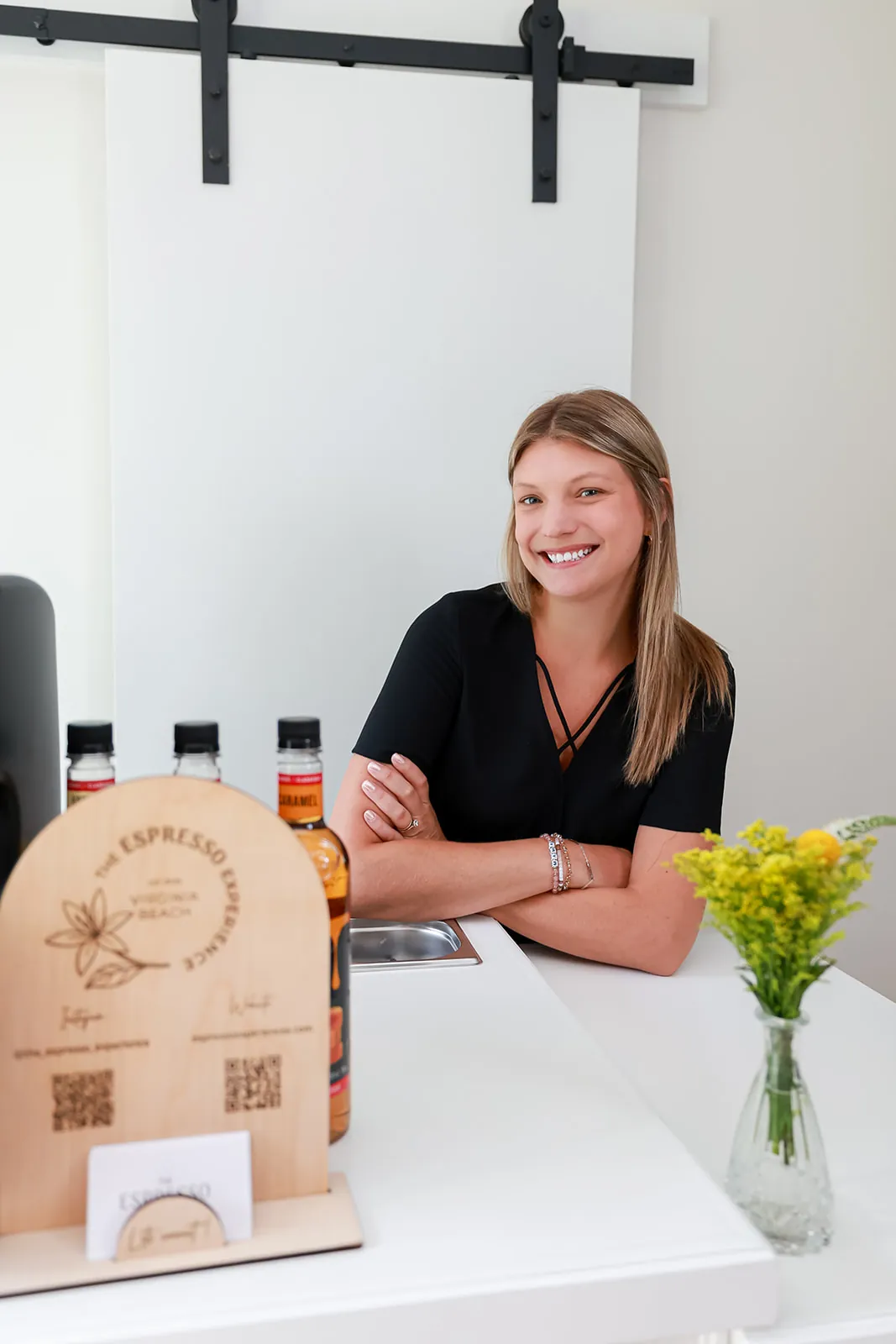 Barista smiling at the espresso cart beside a vase of yellow flowers