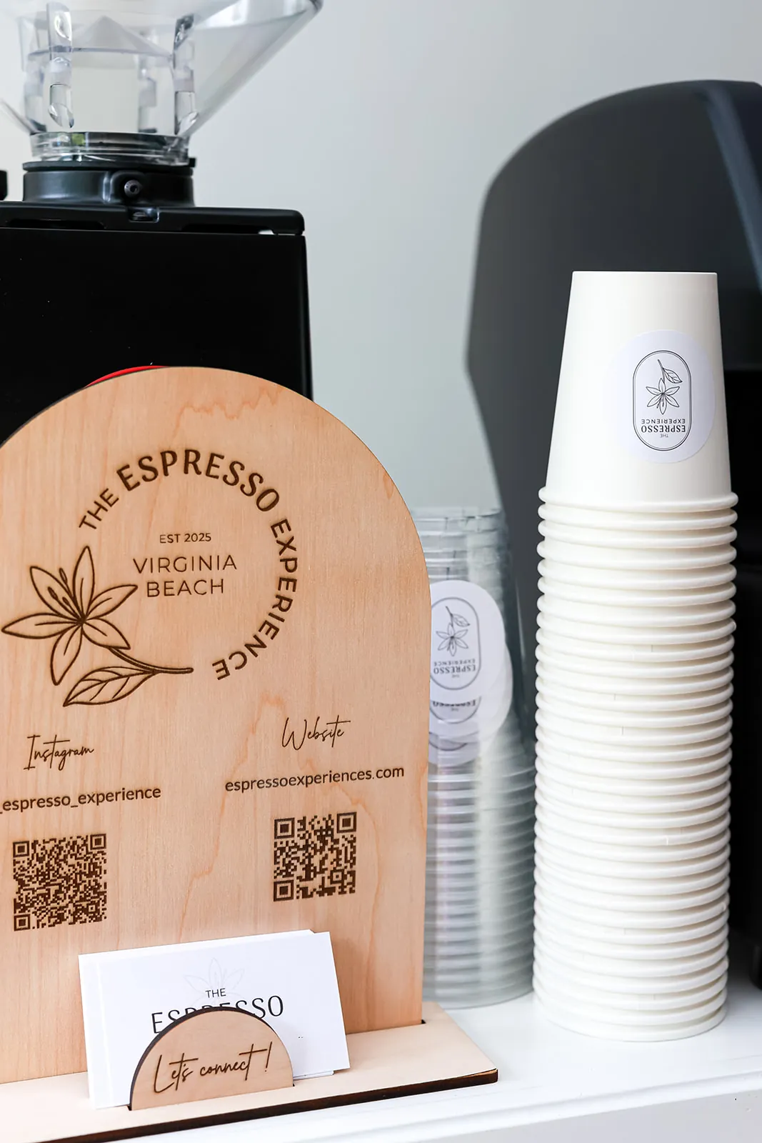 Wooden cart sign with QR codes next to branded paper cups