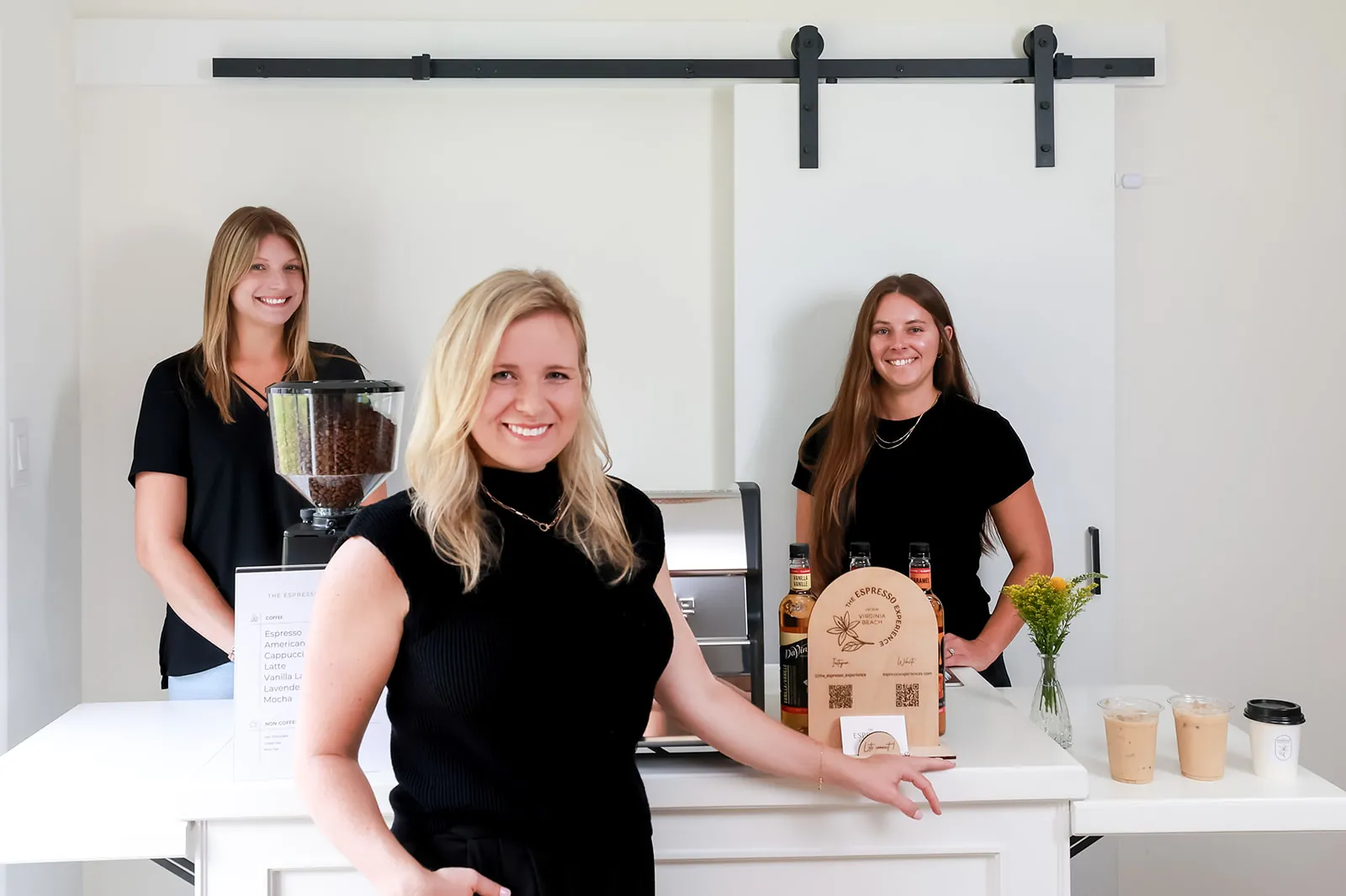 The Espresso Experience team of three smiling behind their white mobile espresso cart