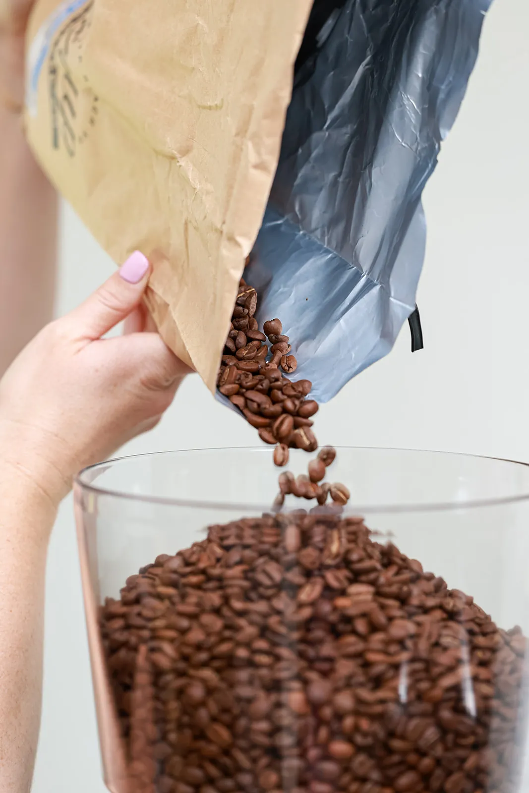 Locally roasted espresso beans pouring from a bag into a glass