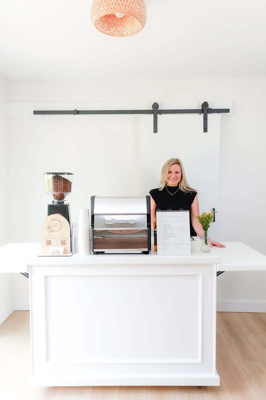 Full view of the white mobile espresso cart with its barista
