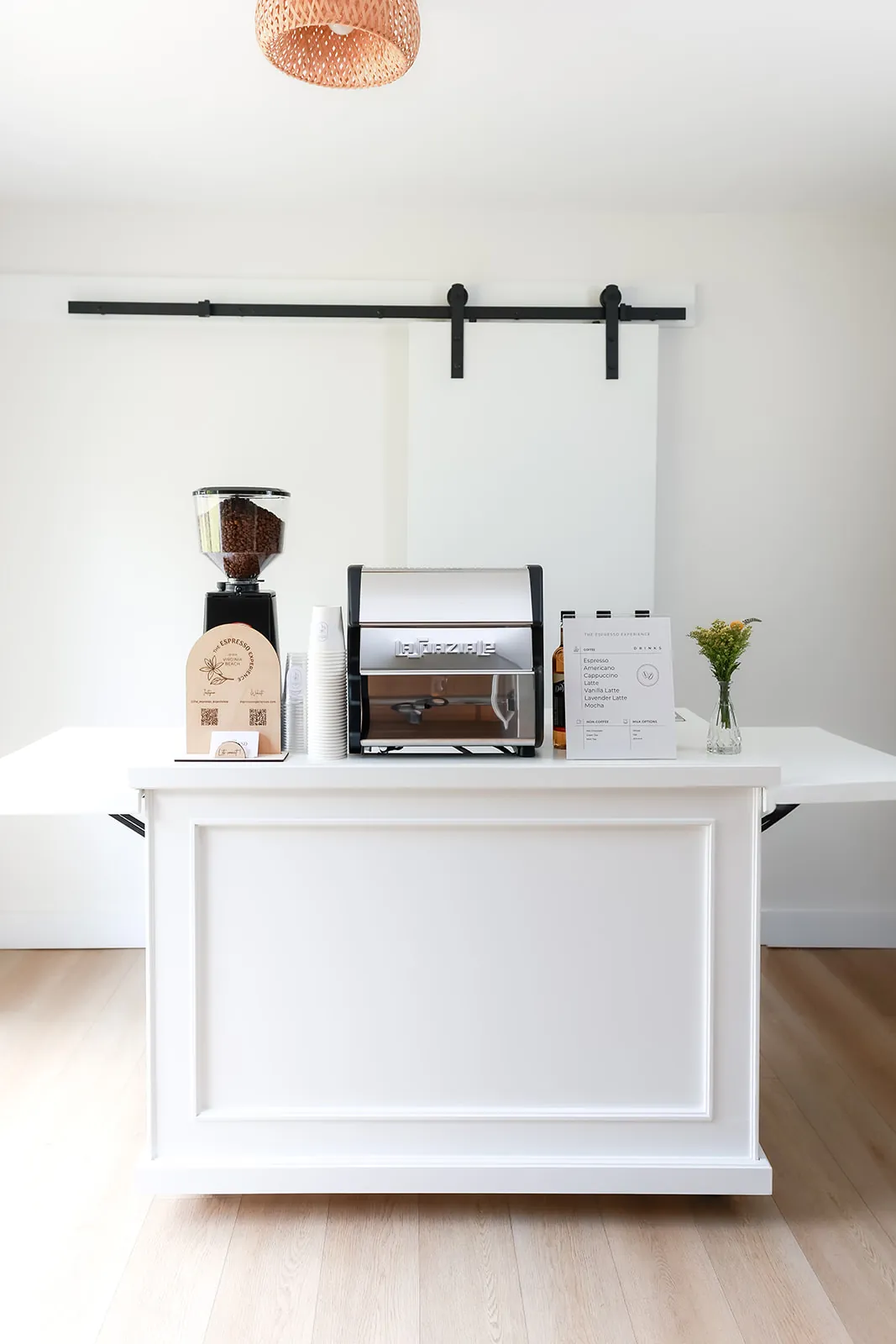 White espresso cart with grinder, machine and wooden sign set up indoors