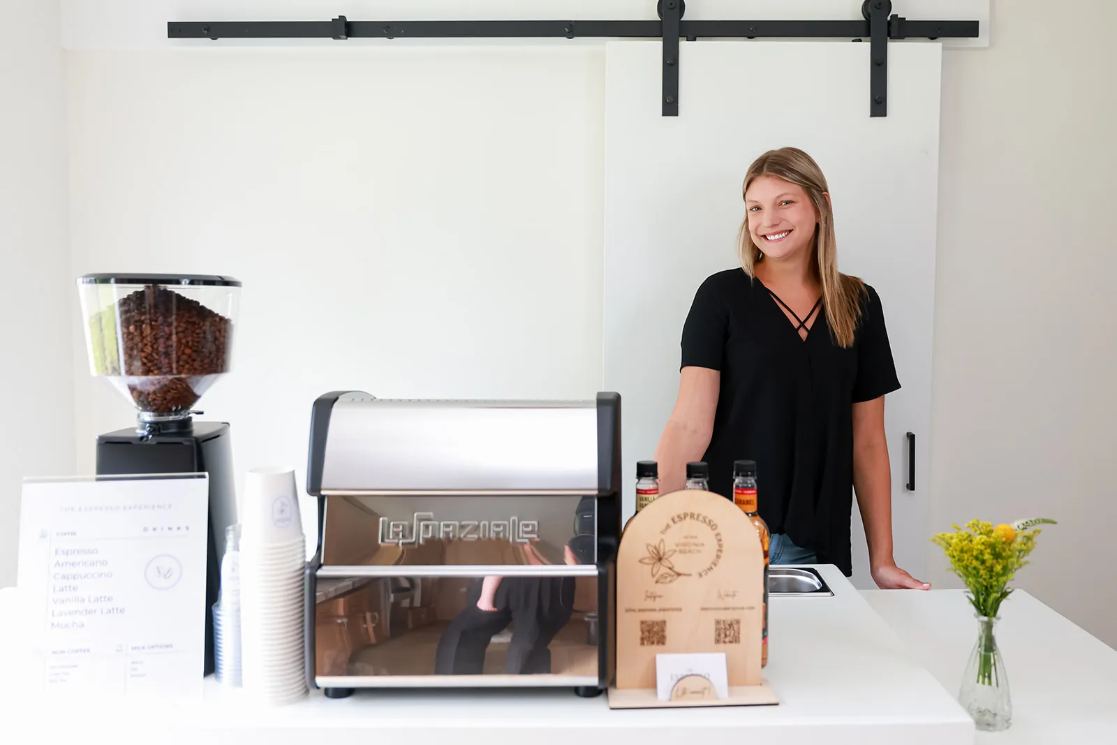 White mobile coffee bar with espresso machine, grinder, menu and fresh flowers
